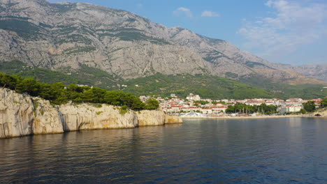Croatian-Makarska-Riviera-town-on-Adriatic-Sea-coast,-aerial-pull-back-view