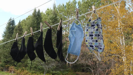 Anti-virus-face-masks-hanging-on-a-clothesline-in-front-of-an-autum-forest-background