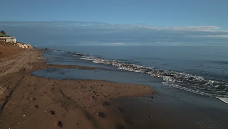 Perspectiva-De-Drones-Del-Hombre-Caminando-En-La-Playa,-Avanzando-Hacia-El-Mar