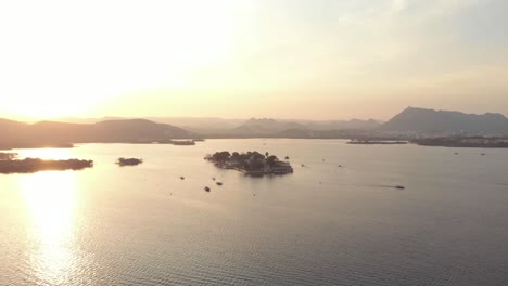 4k-aerial-drone-footage-of-the-Taj-Lake-Palace-of-Lake-Pichola-at-dawn-just-off-the-shoreline-city-of-Udaipur,-India