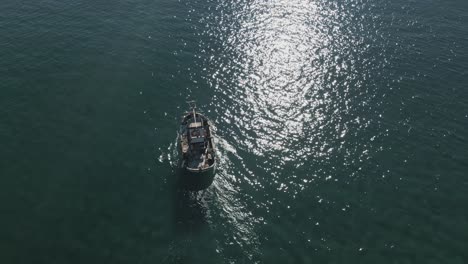 Aerial-view-of-fishing-boat-on-shallow-water,-moving-closer-into-the-horizon