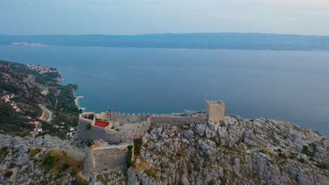Amazing-Omis-Starigrad-Fortress-on-mountaintop-at-sunset,-Croatia,-aerial-view