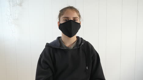 Causasian-Adolescente-Con-Capucha-Negra-Con-Una-Máscara-De-Protección-Antivirus-Negra