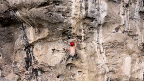 Rock-climber-ascending-a-karst-mountain-rock-face-in-China,-aerial-tracking-view