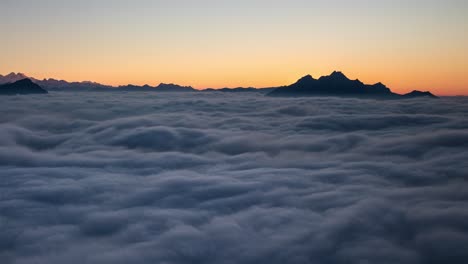 Day-to-night-sunset-time-lapse-above-a-cloud-inversion-in-the-Swiss-Alps-as-seen-from-Rigi,-Switzerland-with-a-view-of-the-mountains-and-stars-and-zoom-out