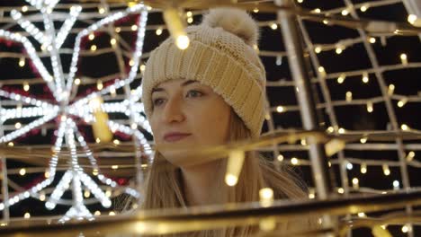 Woman-Walking-On-A-Light-Decorated-Street-at-Night-During-Christmas