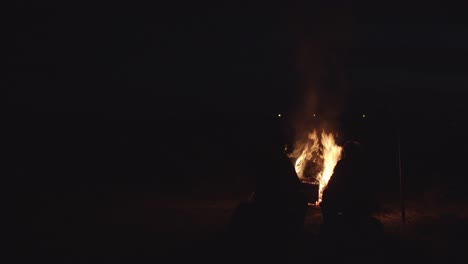 2-Men-Silently-Sitting-By-Big-Campfire-At-Dark-Night