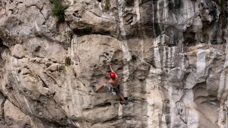 Male-rock-climber-ascending-a-Chinese-karst-mountain-rock-face,-aerial-view