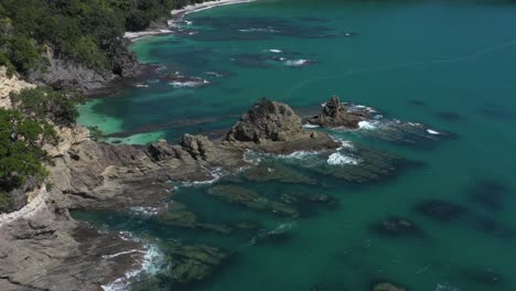 Aerial-of-scenic-rocky-coast-with-stunning-blue-water-at-New-Zealand-shore