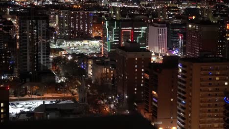 1-2-rooftop-winter-city-semi-birds-eye-view-of-post-modern-residential-retail-commercial-buildings-some-framed-in-LED-green-red-lights-in-the-late-night-evening-with-snow-covered-parked-cars-vehicles