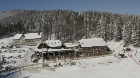 Kope-winter-sports-resort-main-building-in-the-Pohorje-mountains-with-heavy-snowfall,-Aerial-pedestal-down-shot