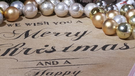 Close-tilt-of-Christmas-decorations-and-greeting-text-on-table-cloth
