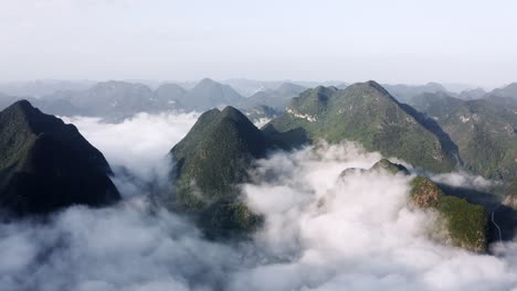 Asian-karst-mountains-rising-above-misty-clouds-in-remote-China,-aerial-view
