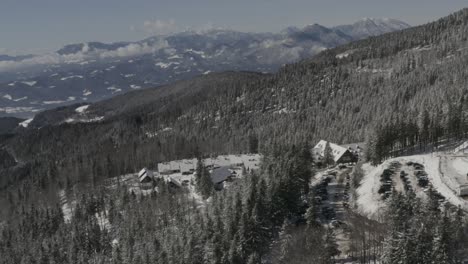 Pohorje-mountains-with-RV-and-car-parking-at-Kope-ski-resort-and-Lukov-dom-in-Mislinja,-Aerial-pan-right-reveal-shot