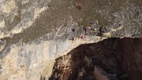 Aerial-shot-of-emergency-team-climbing-down-a-big-rock-in-a-rescue-mission