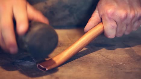 Detail-of-a-man-hammering-a-copper-pipe-over-a-table