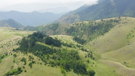 Aerial-landscape-of-the-green-hills-and-Ticje-polje-village,-mountain-Ozren,-Serbia-on-foggy-morning
