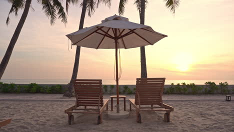 Resort-beach-chairs-and-sun-umbrella-close-to-seashore-at-sunset