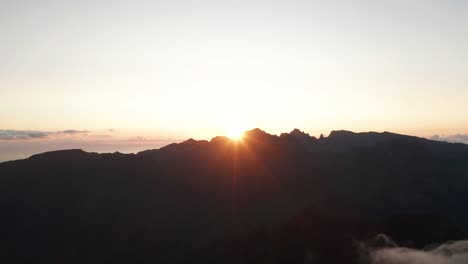 Morning-sun-shines-bright-over-edge-of-mountains-in-Madeira,-aerial