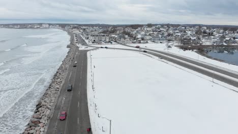 Beautiful-snowy-scene-with-ocean-and-city-in-the-background,-drone-panning-left