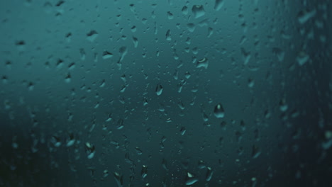 Rain-water-drops-falling-down-on-the-blue-window-glass