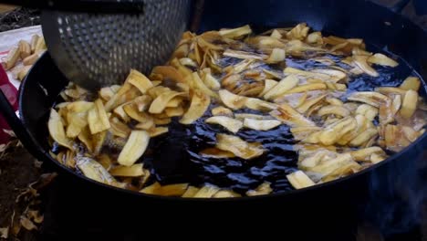 deep-fried-sliced-bananas-with-hot-oil-in-a-pan-on-street-food,-frying-banana-chips-into-the-pan-with-boiling-oil,-Bananas-fried-in-a-pan-with-boiling-oil