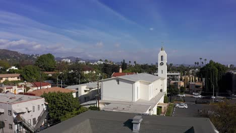 Luftaufnahme,-Die-Sich-über-Die-Dachlinie-Erhebt,-Um-Die-Kirche-Und-Die-Innenstadt-Von-Hollywood-In-Der-Ferne-Zu-Enthüllen