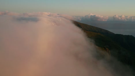 Aerial-lowering-into-mist-flowing-over-mountains-with-windmills-in-Madeira