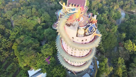 4k-Top-down-Aerial-Cinematic-footage-panning-around-The-Wat-Samphran-Temple-with-huge-dragon-coiled-around-in-Amphoe-Sam-Phran-province-in-Bangkok,-Thailand
