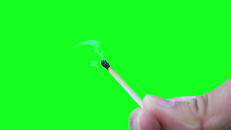 Closeup-hands-hold-burning-matchstick-against-green-screen