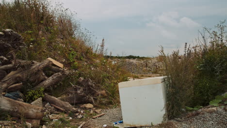Damaged-refrigerator-thrown-out-at-landfill-full-of-demolition-waste-piles