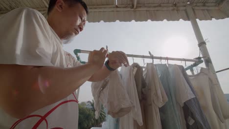 Asian-man-finishes-hanging-clothing-to-dry-on-his-balcony-then-sets-the-timer---slow-motion
