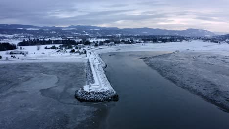 Aerial-shot-over-a-beautiful-river-and-small-village-on-a-winter-day-in-Baie-Saint-Paul