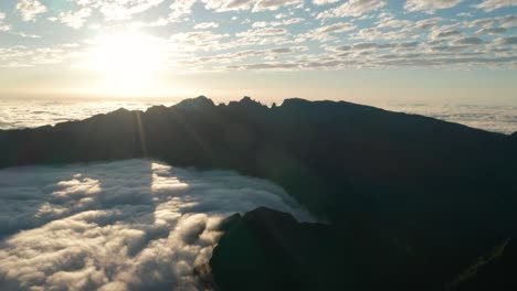 Bright-sun-shines-into-cloud-filled-valley-with-tall-mountains-in-Madeira