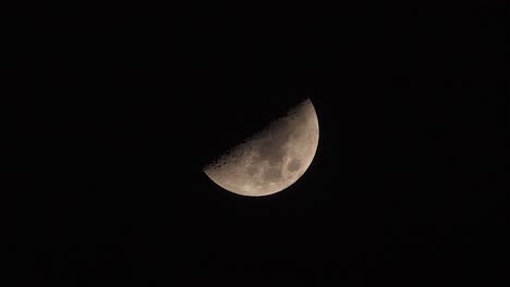 Half-moon-slowly-moving-across-a-dark-black-night-sky