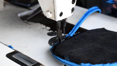 Tailor's-Hands-Stitching-Edges-Of-Bag-Padding-With-A-Sewing-Machine---close-up