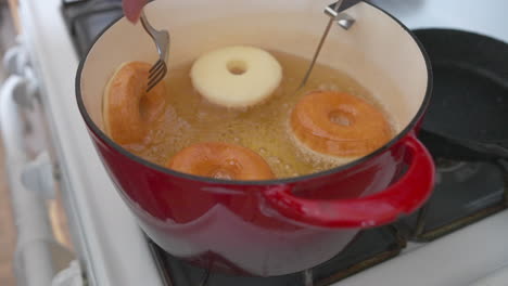Hand-Flips-Donuts-with-Fork-Deep-Frying-in-Pot,-Slow-Motion-Closeup