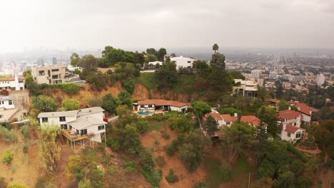 Luftaufnahme-Und-Schwenk-Von-Häusern-In-Den-Hollywood-Hills-Mit-Dunstigem-Los-Angeles-Im-Hintergrund