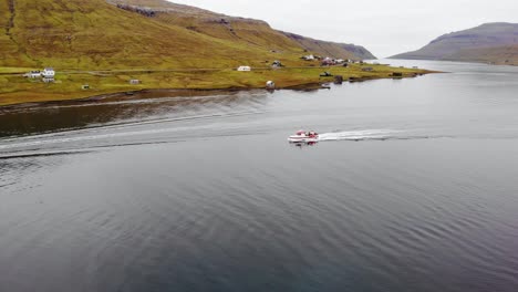 Luftparallaxe-Eines-Kleinen-Bootes,-Das-An-Einem-Bewölkten-Tag-Auf-Den-Färöer-Inseln-Im-Fjord-Inmitten-Einer-Wunderschönen-Berglandschaft-Segelt