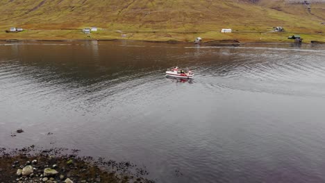 Luftparallaxe-Eines-Bootes,-Das-Durch-Das-Ruhige-Wasser-Im-Wunderschönen-Fjord-Mit-Atemberaubender-Bergkulisse-Auf-Den-Färöer-Inseln-Segelt