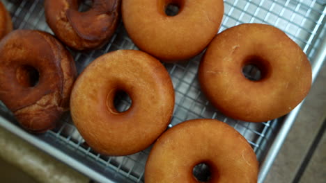 Fresh-Donuts-on-Cooling-Rack,-Overhead-Rotating-Shot