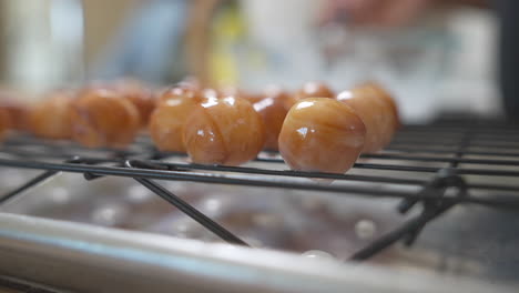 Donut-Löcher-Tropfen-Frische-Glasur-Auf-Kühlregal,-Nahaufnahme-Mit-Weichem-Fokushintergrund