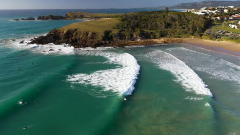 Rotating-drone-shot-of-surfers-in-ocean-revealing-Coffs-Harbour-Australia