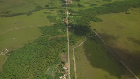 Aerial-view-of-a-long-straight-road-across-a-green-savanna