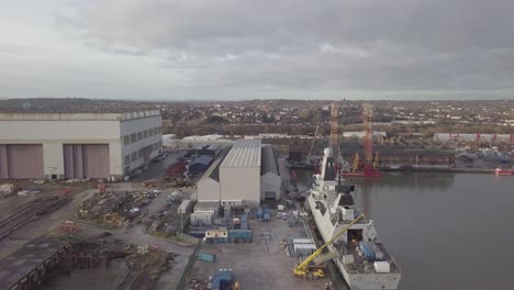 Cammell-Laird-British-industrial-shipyard-aerial-view-servicing-military-naval-ship-Birkenhead-skyline-dolly-right