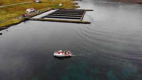 Luftparallaxe-Eines-Bootes,-Das-An-Einem-Kleinen-Hafen-In-Einem-Wunderschönen-Fjord-Mit-Klarem-Wasser-Der-Färöer-Inseln-Ins-Ufer-Segelt