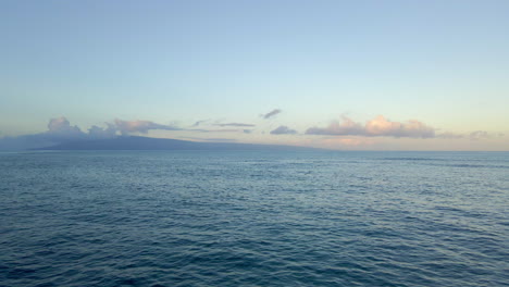 Flying-over-wavy-ocean-towards-silhouette-of-paradise-island-on-horizon