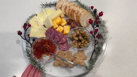 Holiday-cheese-plate-with-assorted-cheese,-nuts,-crackers,-salami,-and-bread