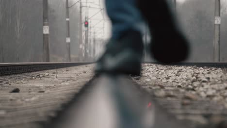 Close-up-view-of-the-foot-in-boots-walks-on-a-steel-railway-track-and-coming-back