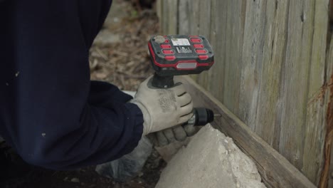 Fixing-An-Old-Wooden-Shed-With-Cordless-Drill,-Hands-In-Gloves